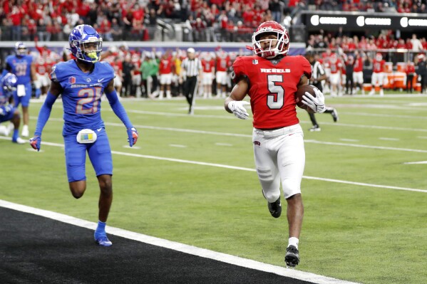 UNLV running back Vincent Davis Jr. (5) runs for a touchdown ahead of Boise State cornerback A'Marion McCoy (21) during the first half of the Mountain West championship NCAA college football game Saturday, Dec. 2, 2023, in Las Vegas. (Steve Marcus/Las Vegas Sun via AP)