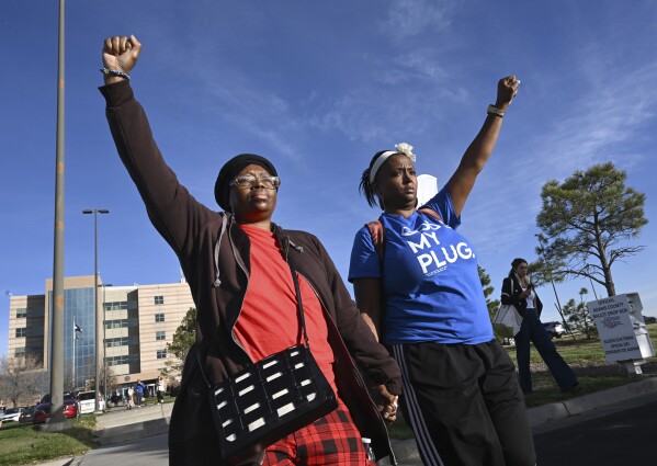 Sheneen McClain, left, mother of Elijah McClain, and friend and supporter MiDian Holmes, right, clasp hands as they hold up their fists in protest over the verdict of a Denver-area police offer who was acquitted in the 2019 death of Elijah, outside of the Adams County Justice Center on Monday, Nov. 6, 2023, in Brighton, Colo. (Helen H. Richardson/The Denver Post via AP)