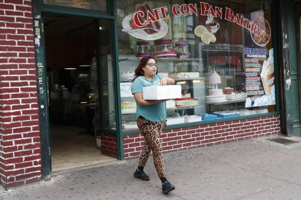 A woman leaves a bakery carrying a cake in the business district of the Sunset Park neighborhood of Brooklyn during the current coronavirus outbreak, Monday, May 11, 2020, in New York. New York Gov. Andrew Cuomo gave the green light to some regions of the state to reopen when the current stay-at-home order expires on Friday. However, New York City, which is still recording as many as 1,000 new cases of coronavirus daily, will not reopen any time soon. (AP Photo/Kathy Willens)