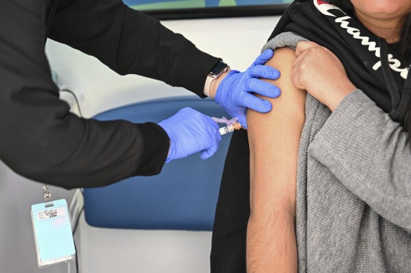 A student receives a vaccination inside a mobile health unit visiting Independence High School in Charlotte, N.C., on Wednesday, March 19, 2025. (AP Photo/Matt Kelley)