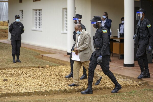 Paul Rusesabagina, center, whose story inspired the film "Hotel Rwanda", is led out in handcuffs from the Kicukiro Primary Court in the capital Kigali, Rwanda Monday, Sept. 14, 2020. A Rwandan court on Monday charged Paul Rusesabagina with terrorism, complicity in murder, and forming an armed rebel group, while Rusesabagina declined to respond to all 13 charges, saying some did not qualify as criminal offenses and saying that he denied the accusations when he was questioned by Rwandan investigators. (AP Photo/Muhizi Olivier)