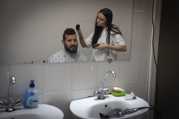 A barber cuts the hair of Checho, 32, a wounded professional soldier from Medellín, Colombia, in a hospital in Ukraine on Wednesday, Dec. 20, 2023. Checho joined the Ukrainian armed forces to help fight Russia. After two years of war, Ukraine is looking for ways to replenish its depleted ranks, and the Colombian army volunteers are a welcome addition. (AP Photo/Efrem Lukatsky)