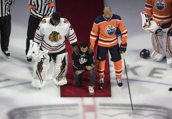 FILE - Minnesota Wild's Matt Dumba takes a knee during the national anthem flanked by Chicago Blackhawks' Malcolm Subban, left, and Edmonton Oilers' Darnell Nurse, before an NHL hockey Stanley Cup playoff game in Edmonton, Alberta, Aug. 1, 2020. Dumba said recently he still sees racism in hockey in the present day, adding he's sick of “the old boys' club and them dictating who is and who isn’t welcome.” (Jason Franson/The Canadian Press via AP, File)