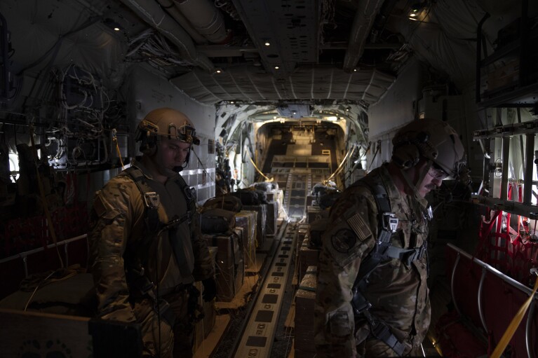 Members of the U.S. Air force stand next to containers with humanitarian aid as they fly toward Gaza Strip after departing from Jordan, Thursday, March 14, 2024. (AP Photo/Leo Correa)