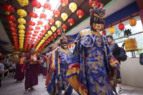 Monks wearing magnificent costumes and masks perform parade in the temple before the Thangka, or traditional painting of Lord Buddha, is unveiled at a Tibetan temple during Wesak day celebration in Ipoh, Malaysia, Wednesday, May 22, 2024. (AP Photo/Vincent Thian)
