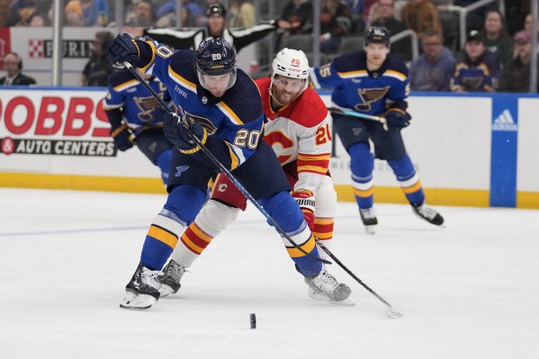 St. Louis Blues' Brandon Saad, left, and Calgary Flames' Blake Coleman battle for a loose puck during the first period of an NHL hockey game Thursday, March 28, 2024, in St. Louis. (AP Photo/Jeff Roberson)