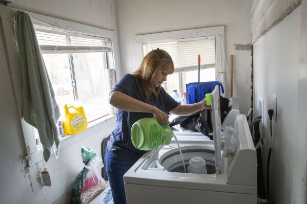 In this Monday, April 27, 2020 photo, Lissette Serrano does laundry while doing her daily chores at home in Bridgeport, Conn., after being let go from her job as a cleaner at a rest stop on the Merritt Parkway in Orange, Conn. Many cleaners of business in the metropolitan New York area have lost their jobs because buildings have shut or because they refuse to work after getting coronavirus symptoms while on the job.   (AP Photo/Mary Altaffer)