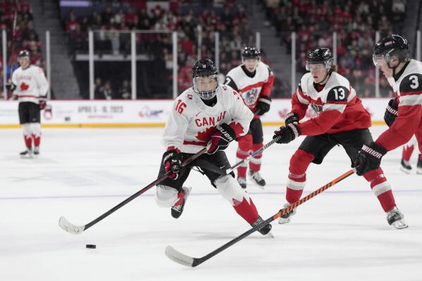 FILE - Canada's Connor Bedard, left, skates past Austria's Lukas Horl, right, and Luca Auer during the second period of a world junior hockey championships game Thursday, Dec. 29, 2022, in Halifax, Nova Scotia. The NHL draft lottery is drawn, determining which team gets the chance to select Connor Bedard with the No. 1 pick. The Anaheim Ducks, Columbus Blue Jackets and Chicago Blackhawks have the highest odds of landing the most anticipated top pick since Connor McDavid in 2015. (Darren Calabrese/The Canadian Press via AP, File)
