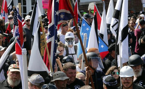 FILE - White nationalist demonstrators walk into the entrance of Lee Park surrounded by counter demonstrators in Charlottesville, Va., Saturday, Aug. 12, 2017.   A jury began deliberations Friday, Nov. 19, 2021, in a civil trial of white nationalists accused of conspiring to commit racially motivated violence at the deadly “Unite the Right” rally in Charlottesville in 2017.(AP Photo/Steve Helber)