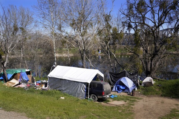 FILE - Tents and other shelters used by people experiencing homelessness stand along the American River Parkway in Sacramento, Calif., Feb. 24, 2022. Tensions are rising in California's capitol city as the Sacramento district attorney on Monday, Aug. 7, 2023, threatened to file charges against city officials over their handling of the homelessness crisis. (AP Photo/Rich Pedroncelli, File)