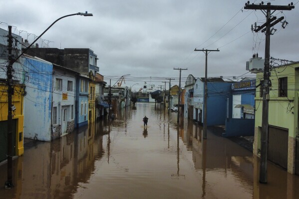 PLIK – Mężczyzna brodzi przez obszar zalany przez ulewne deszcze w Porto Alegre, stan Rio Grande do Sul, Brazylia, 3 maja 2024 r. W świecie coraz bardziej przyzwyczajonym do gwałtownych wahań pogody wydaje się, że ostatnie kilka dni i tygodni trwało przenieść te skrajności środowiskowe na nowy poziom.  (AP Photo/Carlos Macedo, plik)