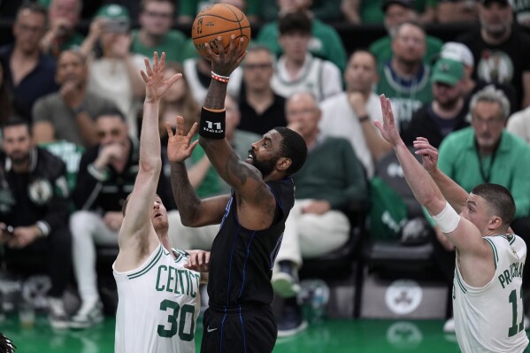 Dallas Mavericks guard Kyrie Irving, center, shoots as Boston Celtics forward Sam Hauser, left, and guard Payton Pritchard defend during the first half of Game 1 of basketball's NBA Finals on Thursday, June 6, 2024, in Boston. (AP Photo/Charles Krupa)