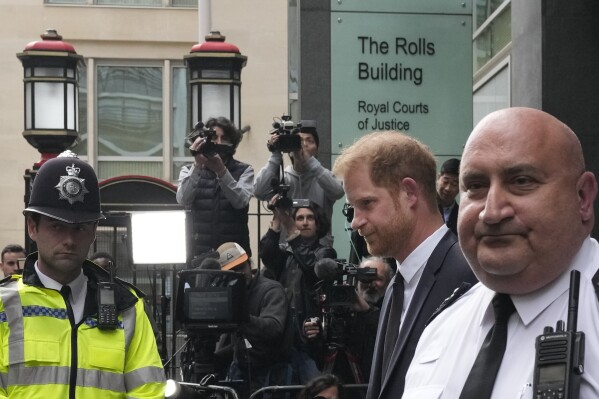 FILE - Prince Harry, second from right, escorted by security leaves the High Court after giving evidence in London, Tuesday, June 6, 2023. Prince Harry is challenging on Tuesday, Dec. 5, 2023, the British government’s decision to strip him of his security detail after he gave up his status as a working member of the royal family and moved to the United States. The Duke of Sussex said he wants protection when he visits home and claimed it's partly because an aggressive press jeopardizes his safety and that of his family. (AP Photo/Frank Augstein, File)