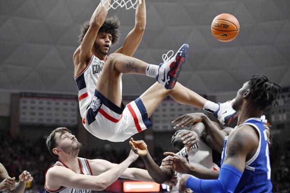 UConn's Andre Jackson Jr. dunks over teammates Alex Karaban, left, and Adama Sanogo in the second half of an NCAA college basketball game, Saturday, Feb. 18, 2023, in Storrs, Conn. (AP Photo/Jessica Hill)