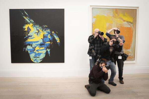 Photographers take photos near to the artwork, Andy Warhol, Self-Portrait, 1986, during a photo call for artworks from the Macklowe Collection at Sotheby's, prior to the collection being offered at auction in New York, in London, Friday, Feb. 18, 2022. Artworks by Pablo Picasso, Mark Rothko and Andy Warhol and other modern masters are going up for auction in a sale ordered by a U.S. court as part of a billionaire couple’s acrimonious divorce.  The works belonged to property developer Harry Macklowe and his wife Linda, who spent 40 years assembling a collection by some of the 20th century’s greatest artists, displaying many of them in their grand apartment in New York’s Plaza building. (Stefan Rousseau/PA via AP)