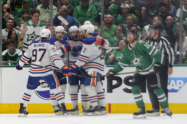 Edmonton Oilers' Connor McDavid (97), Ryan Nugent-Hopkins (3), Zach Hyman (18), Leon Draisaitl (29) and Evan Bouchard (2) celebrate a goal scored by Nugent-Hopkins as Dallas Stars' Ty Dellandrea (10) skates past during the first period of Game 5 of the Western Conference finals in the NHL hockey Stanley Cup playoffs Friday, May 31, 2024, in Dallas. (AP Photo/Julio Cortez)