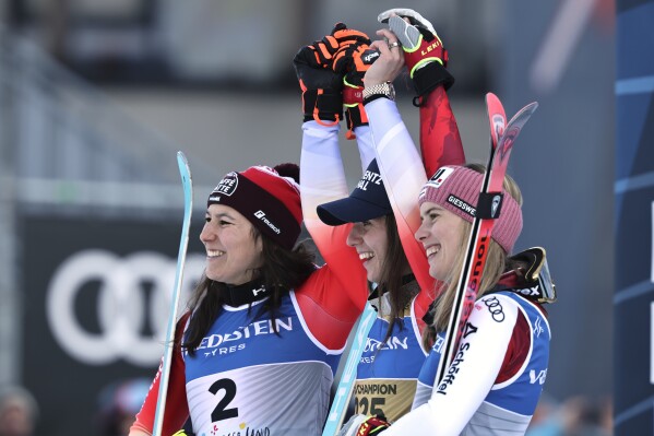 Switzerland's Camille Rast, center, winner of a gold medal in a women's slalom, celebrates on the podium with silver medalist Switzerland's Wendy Holdener, left, and bronze medalist Austria's Katharina Liensberger, at the Alpine Ski World Championships, in Saalbach-Hinterglemm, Austria, Saturday, Feb. 15, 2025. (AP Photo/Marco Trovati)