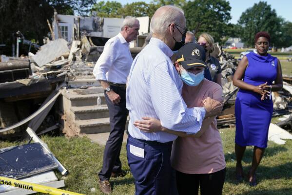 President Joe Biden talks with a person as he tours a neighborhood impacted by Hurricane Ida, Tuesday, Sept. 7, 2021, in Manville, N.J. New Jersey Gov. Phil Murphy, left, and Somerset County Commissioner President Shanel Robinson, right, look on. (AP Photo/Evan Vucci)