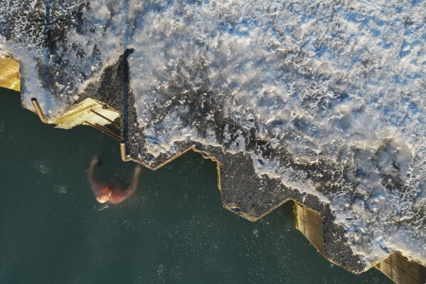 ФАЙЛ — Джордж Миллер вылезает из ледяных вод озера Мичиган, 2 февраля 2023 года, в Чикаго.  Федеральные метеорологи в пятницу, 8 марта, официально заявили: это самая теплая зима в США за всю историю наблюдений.  (AP Photo/Эрин Хули, файл)