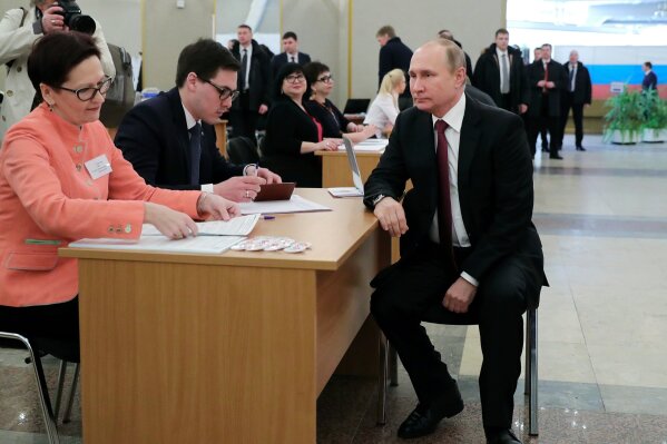 
              Russian President and Presidential candidate Vladimir Putin waits to get his ballot as he arrives to vote at a polling station during Russia's presidential election in Moscow, Russia, Sunday, March 18, 2018. Putin's victory in Russia's presidential election Sunday isn't in doubt. The only real question is whether voters will turn out in big enough numbers to hand him a convincing mandate for his fourth term and many Russian workers are facing intense pressure to do so. (Mikhail Klimentyev, Sputnik, Kremlin Pool Photo via AP)
            