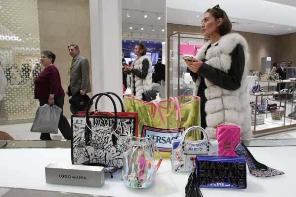 FILE - In this March 14, 2019 file photo a woman shops at Neiman Marcus during the opening night of The Shops & Restaurants at Hudson Yards in New York. Retailers and consumer product makers like American Textile may have received some short moment of reprieve after the Trump Administration delayed the 10% tariffs on some products which also include toys, clothing and shoes. (AP Photo/Mark Lennihan, File)