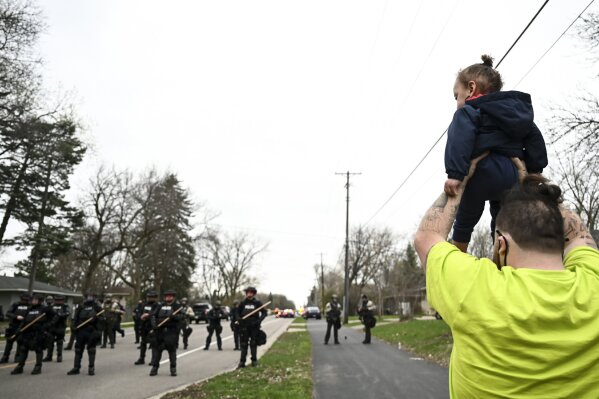 Damik Wright, brother of Daunte Wright, who the family said was shot and killed earlier Sunday by police, holds Daunte's son Daunte Jr., over his head to look at police officers assembling with riot gear at 63rd Avenue North and Lee Avenue North, Sunday, April 11, 2021, in Brooklyn Center, Minn. (Aaron Lavinsky/Star Tribune via AP)