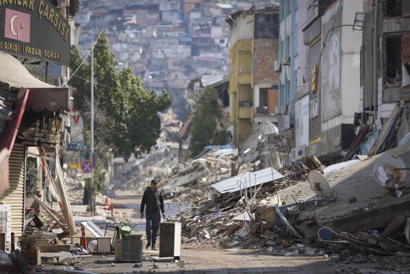 A man walks past destroyed buildings in Antakya, southeastern Turkey, Tuesday, Feb. 21, 2023. The death toll in Turkey and Syria rose to eight in a new and powerful earthquake that struck two weeks after a devastating temblor killed nearly 45,000 people, authorities and media said Tuesday. (AP Photo/Unal Cam)