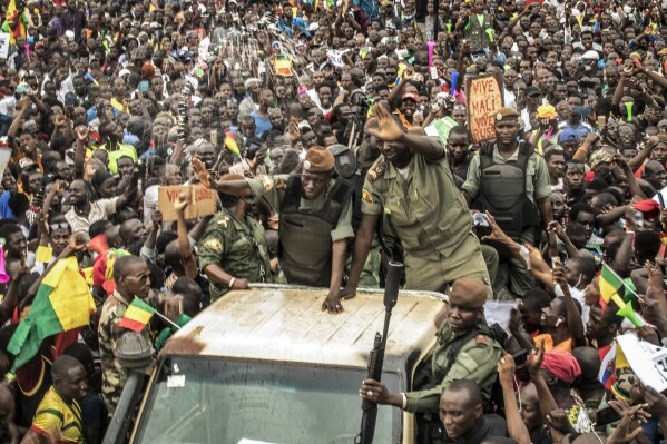 FILE - An unidentified representative of the junta waves from a military vehicle as Malians supporting the overthrow of President Ibrahim Boubacar Keita gathers to celebrate in the capital Bamako, Mali., on Aug. 21, 2020. Mali recalled its ambassador in Algeria after accusing it of interference in its internal affairs by meeting rebel leaders, officials said Friday, Dec. 22, 2023, deepening diplomatic tensions between the two neighbors over efforts to end the armed rebellion in northern Mali. (AP Photo, File)