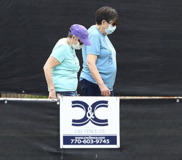 A pair of women behind a blackened fence where quarantined Grand Princess cruise ship passengers are isolated in a housing area at Dobbins Air Reserve Base on Thursday, March 12, 2020, in Marietta, Ga. "Prior to arriving here, the passengers were medically screened by the U.S. Department of Health and Human Services and Centers for Disease Control and Prevention," said Col. Craig McPike, Dobbins installation commander. "The passengers who were asymptomatic were transferred here and other federal military installations for COVID-19 testing and quarantine." Should any individuals be identified as ill during their quarantine period, the Department of Health & Human Services, the lead federal agency, has procedures in place to transport them to a local civilian hospital. "CDC is fully responsible for all aspects of the quarantine operation, and Dobbins personnel will have no contact with these passengers.  (Curtis Compton/Atlanta Journal-Constitution via AP)