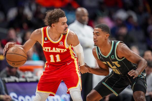 Atlanta Hawks guard Trae Young (11) is guarded by Charlotte Hornets guard Theo Maledon (9) during the first half of an NBA basketball game Friday, Dec. 16, 2022, in Charlotte, N.C. (AP Photo/Rusty Jones)