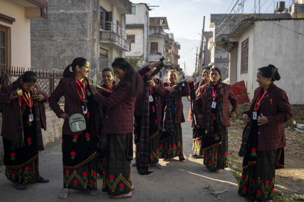 Shanti Chaudhari, front center, helps a band member get ready to perform at a wedding in Kathmandu, Nepal, Wednesday, March 6, 2024. As a child, Chaudhari was scolded by her parents for standing too close to a group of musicians playing the naumati baja, Nepal's nine traditional instruments, because they were identified with the Damai, part of the lowest caste that was formerly known as “untouchables.” (AP Photo/Niranjan Shrestha)