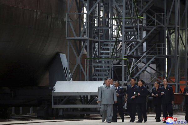 In this undated photo provided on Tuesday, July 23, 2019, by the North Korean government, North Korean leader Kim Jong Un, left, inspects a newly built submarine to be deployed soon, at an unknown ...