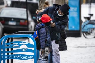 FILE - A man adjusts a boy's face mask as they arrive at Jordan Community Public School in Rogers Park on the North Side, Wednesday, Jan. 12, 2022, in Chicago. Illinois Attorney General Kwame Raoul filed a notice to appeal, Monday, Feb. 7, 2022, after a judge the week before declared that Gov. J.B. Pritzker's mask requirement for schools overstepped legal bounds. Meanwhile, schools were acting cautiously on whether students and staff members needed to wear masks to stem the spread of COVID-19. (Ashlee Rezin /Chicago Sun-Times via AP, File)