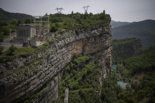 Power facilities are pictured on the hydroelectric dam of the Lac de Castillon in southern France, Tuesday, June 20, 2023. Human-caused climate change is lengthening droughts in southern France, meaning the reservoirs are increasingly drained to lower levels to maintain the power generation and water supply needed for nearby towns and cities. (AP Photo/Daniel Cole)