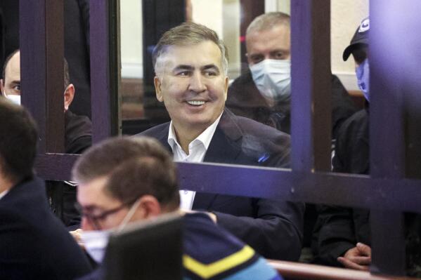 Former Georgian President Mikheil Saakashvili who was convicted in absentia of abuse of power during his presidency and arrested upon his return from exile, smiles standing inside a defendant's dock during a court hearing in Tbilisi, Georgia, Monday, Nov. 29, 2021. Saakashvili, who was president from 2008-13, left Georgia after the end of his second term and was later convicted in absentia of abuse of power. He was arrested on Oct. 1 after returning to Georgia to try to bolster opposition forces in the run-up to nationwide municipal elections. (Irakli Gedenidze/Pool Photo via AP)