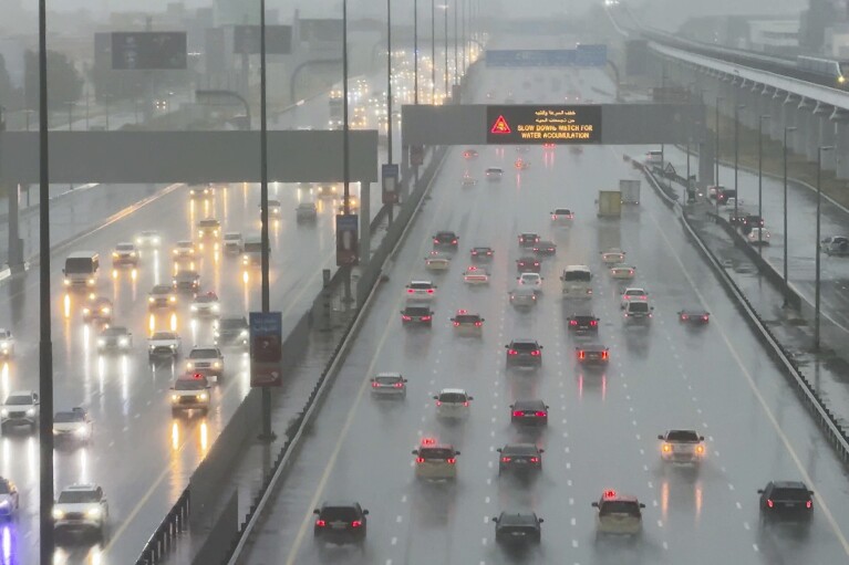 Vehicles drive through heavy rain on the Sheikh Zayed Road highway in Dubai, United Arab Emirates, Tuesday, April 16, 2024. Heavy rains lashed the United Arab Emirates on Tuesday, flooding out portions of major highways and leaving vehicles abandoned on roadways across Dubai. Meanwhile, the death toll in separate heavy flooding in neighboring Oman rose to 18 with others still missing as the sultanate prepared for the storm. (AP Photo/Jon Gambrell)