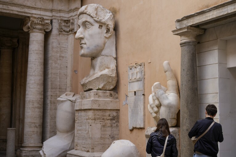 People admire the surviving portions of the statue of Roman Emperor Constantine the Great (c. 280–337) commissioned for himself after 312 AD, on display in a courtyard of the Capitoline Museums, in Rome, Tuesday, Feb. 6, 2024. The museum unveiled in one of its side gardens a massive, 13-meter (yard) replica of the statue built using 3D technology from scans of the nine giant original marble body parts that remain. (AP Photo/Andrew Medichini)