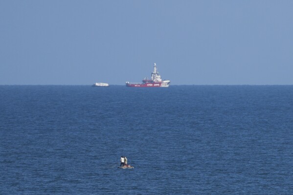 A ship belonging to the Open Arms aid group approaches the shores of Gaza towing a barge with 200 tons of humanitarian aid on Friday, March 15, 2024. (AP Photo/Abdel Kareem Hana)