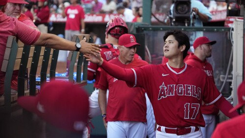 Los Angeles Angels' Shohei Ohtani, right, greets players in the dugout prior to a baseball game against the New York Yankees Tuesday, July 18, 2023, in Anaheim, Calif. (AP Photo/Mark J. Terrill)