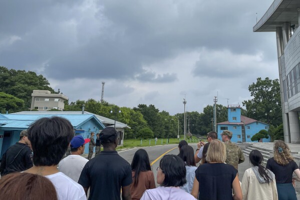 A group of tourists stand near a border station at Panmunjom in the Demilitarized Zone in Paju, South Korea, Tuesday, July 18, 2023. Not long after this photo was taken, Travis King, a U.S. soldier, bolted across the border and became the first known American detained in the North in nearly five years. (AP Photo/Sarah Jane Leslie)