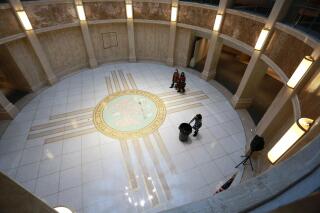 FILE - People walk under the state Capitol rotunda during the annual legislative session on Feb. 2, 2022, in Santa Fe, N.M. A legislative panel on Tuesday, July 12, 2022, listened to advocates who hope to broaden the scope of medical treatment and research assisted by psilocybin, the psychedelic active ingredient in certain mushrooms. (AP Photo/Cedar Attanasio, File)