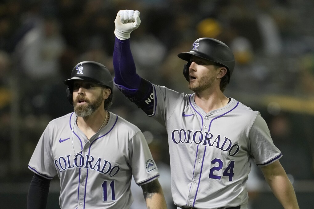 Colorado Rockies' Ryan McMahon (24) gestures after hitting a two-run home run that scored Jake Cave (11) during the 12th inning of the team's baseball game against the Oakland Athletics in Oakland, Calif., Wednesday, May 22, 2024. (AP Photo/Jeff Chiu)