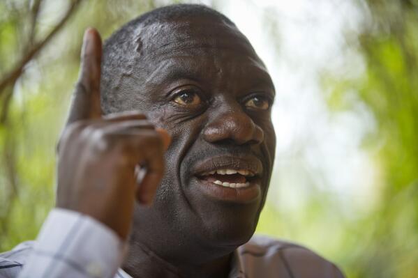 FILE - Opposition politician and then presidential candidate Kizza Besigye speaks to the media while under house arrest, at his home in Kasangati, outside the capital Kampala, in Uganda on Feb. 21, 2016. Besigye, a four-time presidential candidate who has been calling for street protests against rising commodity prices, has been unable to leave his home since May 12, 2022 with police pitching camp nearby to enforce his apparent house arrest. (AP Photo/Ben Curtis, File)