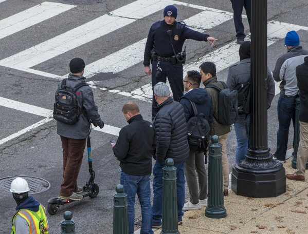 In this Dec. 5, 2018, photo, a police officer directs a rider on a Skip brand electric scooter to move off the street on Capitol Hill in Washington. As electric scooters have rolled into more than 100 cities worldwide, many of the people riding them have ended up in the emergency room with serious injuries. Others have been killed. (AP Photo/J. Scott Applewhite)