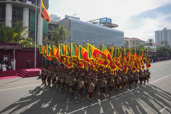 Sri Lankan government soldiers march carrying national flags during the 75th Independence Day ceremony in Colombo, Sri Lanka, Saturday, Feb. 4, 2023. Sri Lanka marks the anniversary of independence from British colonial rule on Feb. 4 each year. (AP Photo/Eranga Jayawardena)