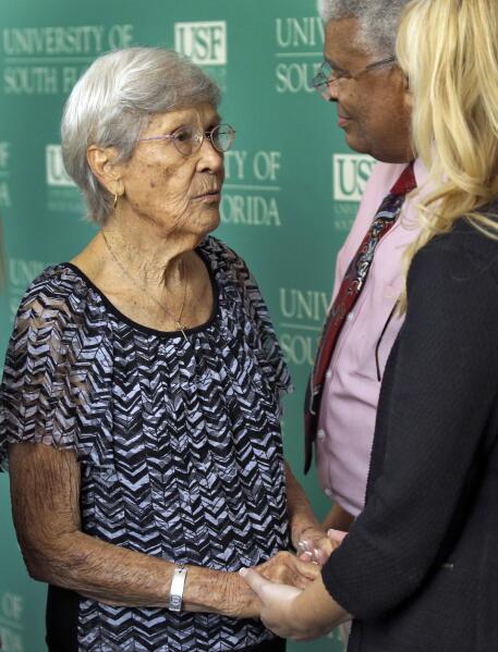 Ovell Krell, left, sister of George Owen Smith, the first victim positively identified from one of the 55 unmarked graves the former Arthur G. Dozier School for Boys in Marianna, Fla.,  shakes hands with University of South Florida lead researcher Dr. Erin Kimmerle, right, and Paul Douglas of the NAACP, after a news conference Thursday, Aug. 7, 2014, at the university in Tampa, Fla.  University researchers will exhume Smith's remains and return them to his family. Smith was 14 when he was sent to the school in 1940, and was never seen alive by his family again.  (AP Photo/Chris O'Meara)