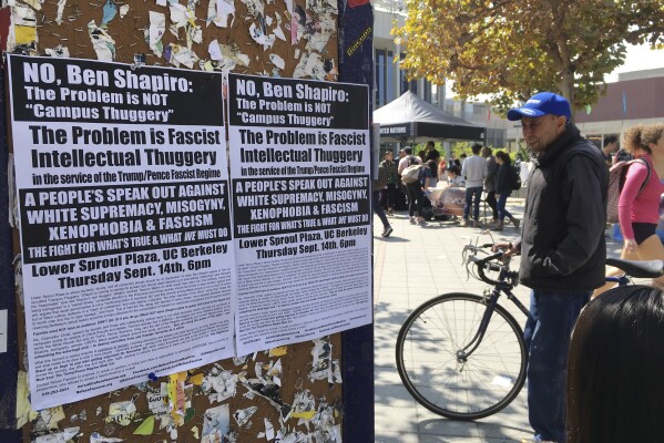 FILE - A man stands by flyers on a University of California, Berkeley campus bulletin board calling for a protest against right-wing speaker Ben Shapiro in Berkeley, Calif., Sept. 8, 2017. New polling finds that America’s college campuses are seen as far friendlier to liberals than to conservatives when it comes free speech. Polling from the University of Chicago and the AP-NORC Center for Public Affairs Research finds that 47% of adult Americans say liberals are free to express their views on college campuses, while 20% said the same of conservatives. (AP Photo/Jocelyn Gecker, File)