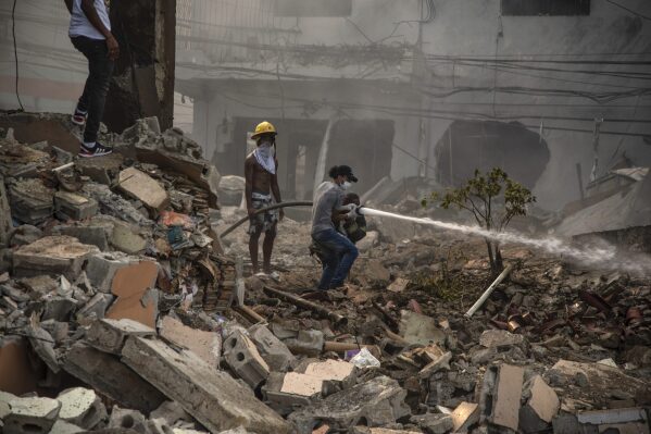 Firefighters put out a fire after a powerful explosion in San Cristobal, Dominican Republic, Monday, Aug 14, 2023. The Monday afternoon explosion killed at least three people and injured more than 30 others, authorities said. (Jolivel Brito/Diario Libre via AP)
