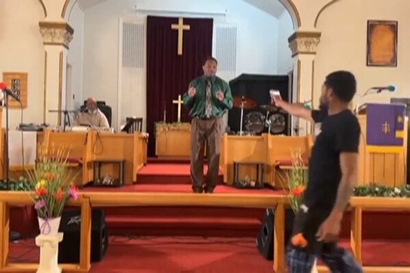 In this image taken from video, a Bernard J. Polite, 26, tries to shoot Pastor Glenn Germany, center, at the Jesus Dwelling Place church in North Braddock, Pa., May 5, 2024. The attempted shooting failed when Polite's gun didn't fire and was tackled by a congregant. (Glenn Germany via AP)