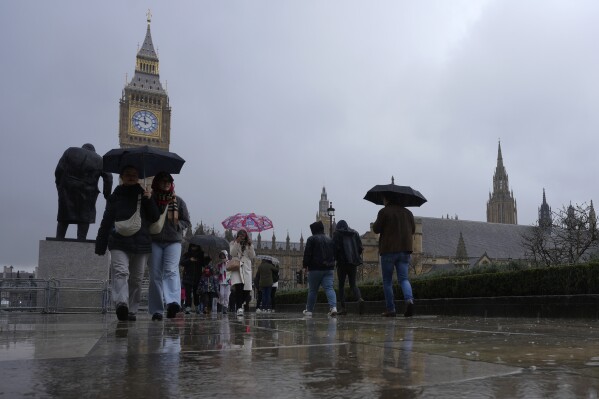 Tourists hold umbrellas against the rain as they walk in Parliament Square next to the the Houses of Parliament in London, Thursday, Feb. 22, 2024. U.K. lawmakers have called for a cease-fire in the Israel-Hamas war. But the move came after dozens of lawmakers walked out of the House of Commons in protest at how the vote was handled on Wednesday. (AP Photo/Alastair Grant)